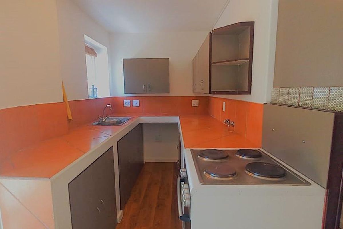 A compact kitchen featuring tiled countertops, built-in cabinetry, and a freestanding electric stove, offering a functional layout with potential for modernization.