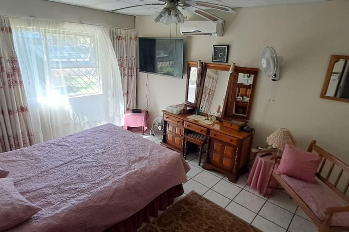 A bedroom featuring tiled flooring, a ceiling fan, and a wall-mounted air conditioning unit.