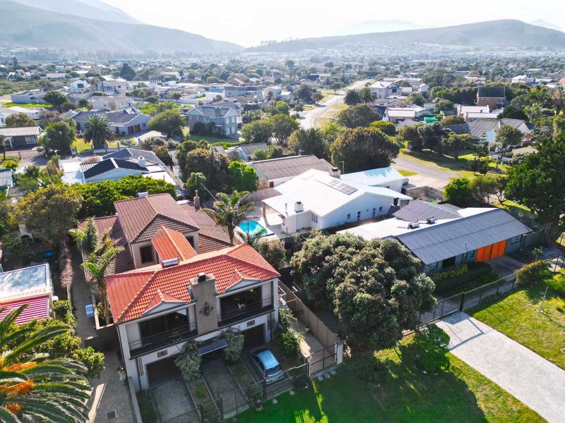 Aerial view of the residential property showcasing the roof structure, swimming pool, paved driveway, and surrounding neighbourhood landscape.