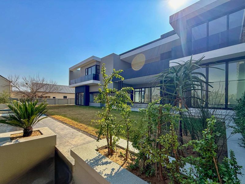 Modern rear elevation featuring expansive glass sliding doors, sleek architectural lines, and a well-maintained garden with raised planters.
