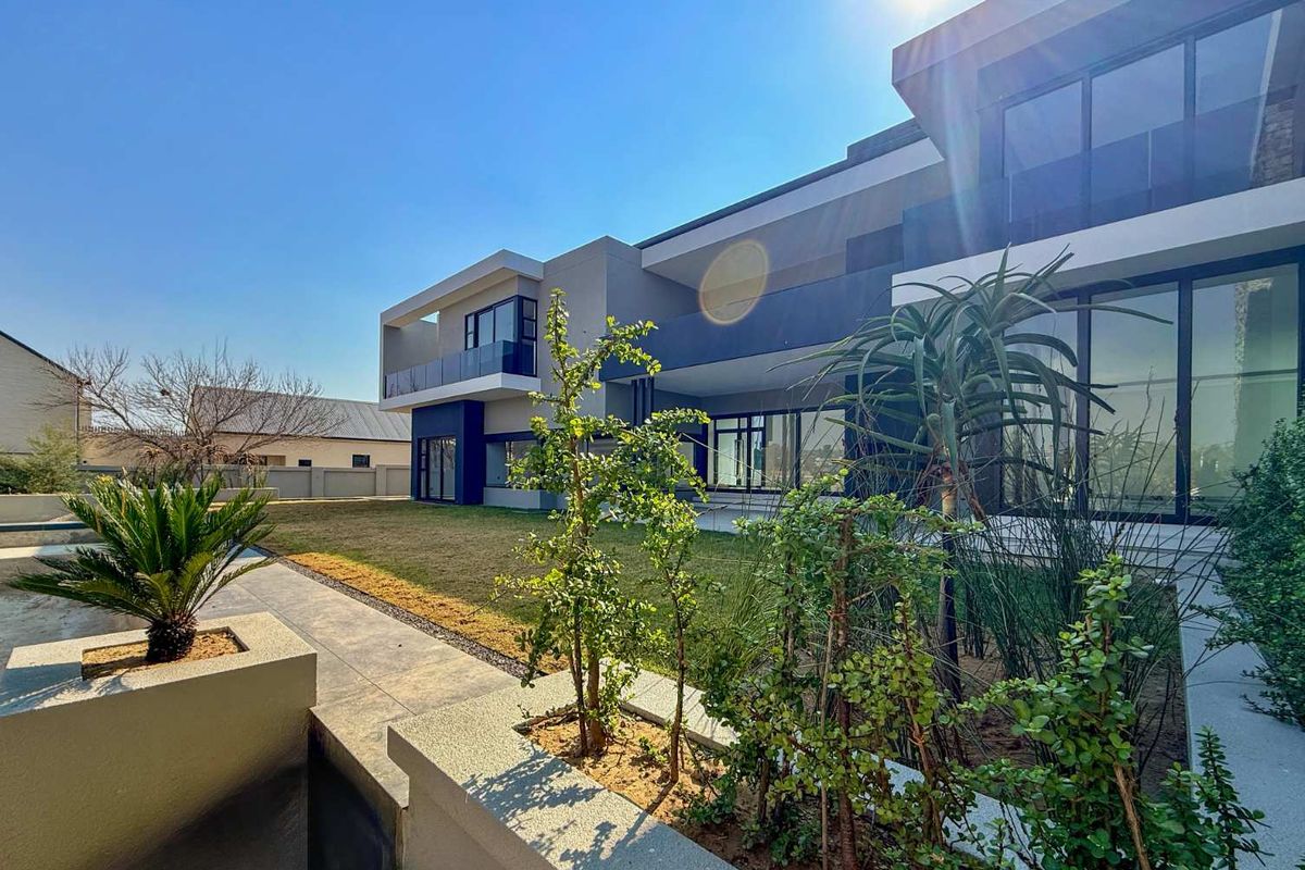 Modern rear elevation featuring expansive glass sliding doors, sleek architectural lines, and a well-maintained garden with raised planters.