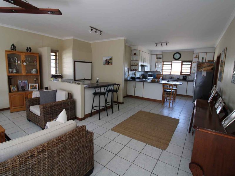 Open plan living and kitchen area featuring tiled flooring, a breakfast bar, and functional cabinetry, offering a versatile space for daily living.