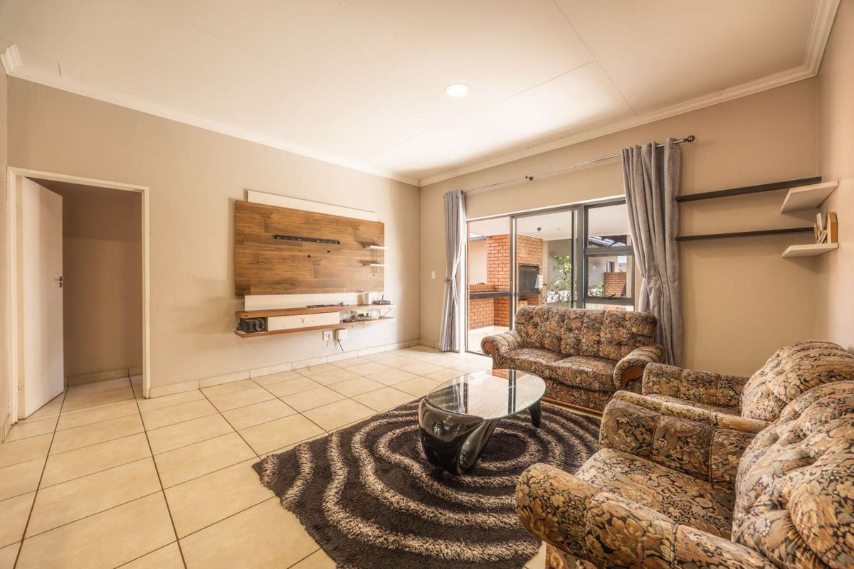 Spacious living room featuring neutral tiled flooring, a built-in media console, and large sliding glass doors providing access to the outdoor patio area.