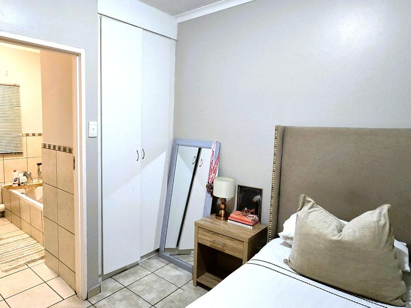 A bedroom featuring tiled flooring, a built-in wardrobe, and direct access to an en-suite bathroom with a bathtub.
