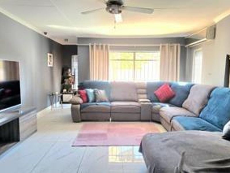 Spacious living room featuring tiled flooring, a ceiling fan, and a wall-mounted air conditioning unit.