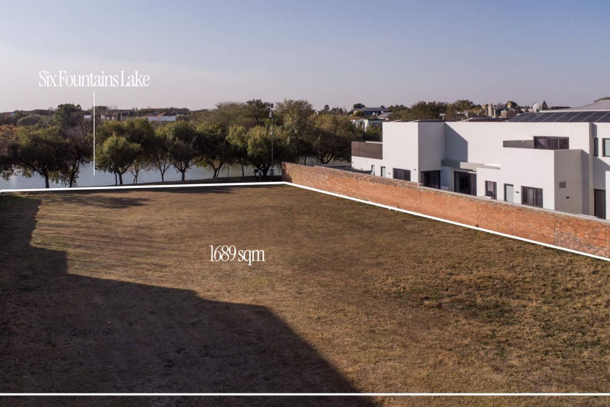 An aerial view of a 1689sqm vacant residential plot featuring perimeter brick boundary walls and proximity to the Six Fountains Lake.
