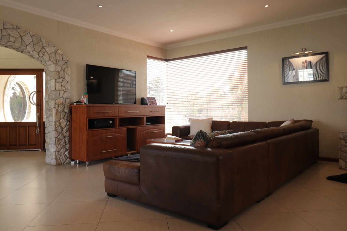 Spacious living room featuring tiled flooring, recessed downlighting, and a distinctive stone-clad archway leading to the entrance.