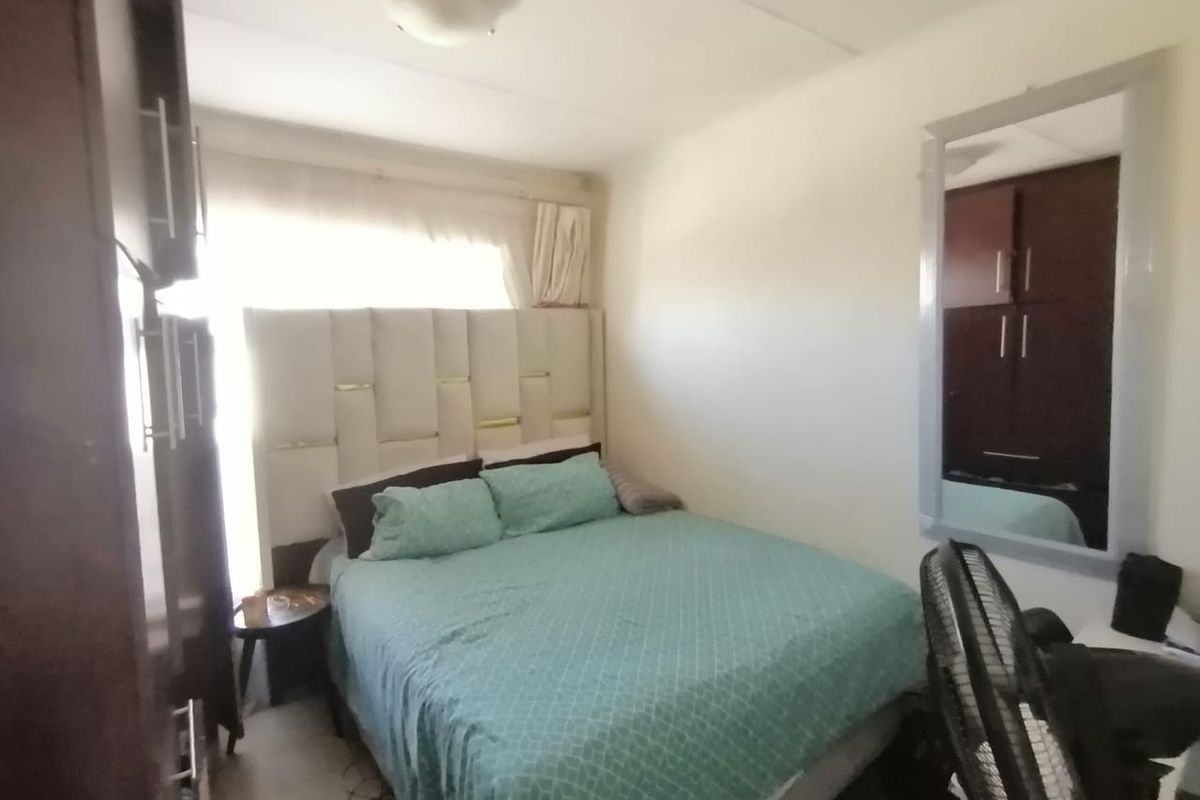 A functional bedroom featuring built-in wooden cabinetry and a large window, providing a comfortable and practical living space.