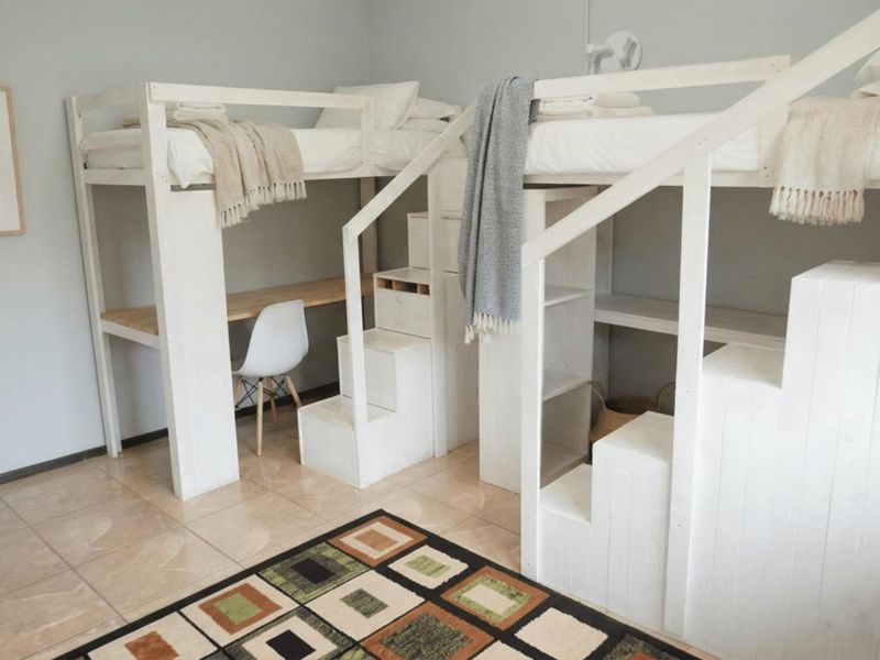 A bedroom featuring tiled flooring and custom built-in loft bed structures with integrated staircases and desk space.