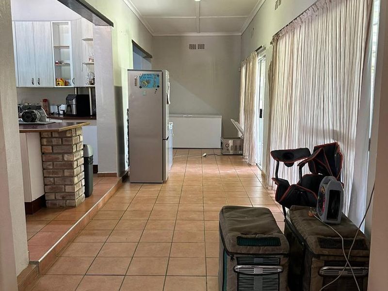 Open plan kitchen and living area featuring tiled flooring, a brick breakfast bar, and sliding glass doors leading to the exterior.