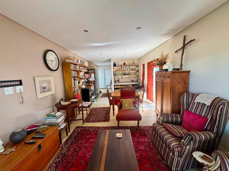 An open-plan living and dining area featuring tiled flooring, recessed downlighting, and integrated shelving, offering a versatile space for relaxation and meals.