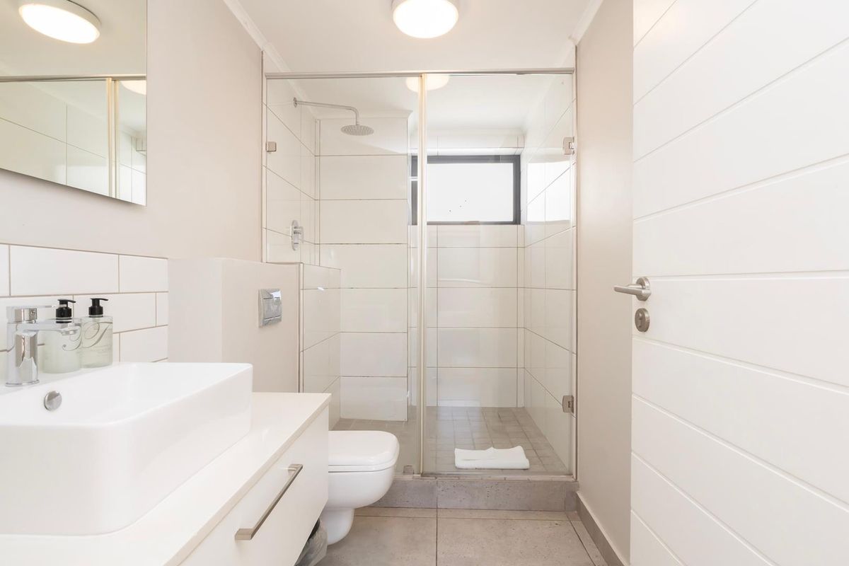 Modern bathroom featuring a wall-mounted vanity with vessel sink, wall-hung toilet, and a spacious walk-in shower with glass enclosure and tiled finishes.