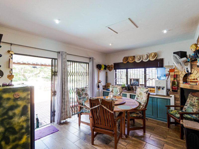 A functional kitchen area featuring built-in cabinetry, a brick fireplace, and direct access to the outdoor patio through a sliding security gate.