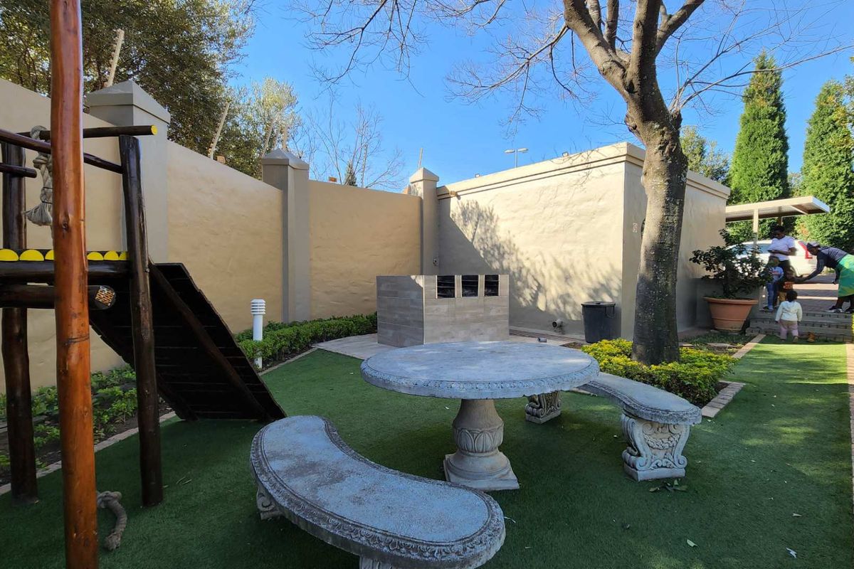Communal outdoor area featuring a built-in braai, artificial lawn, and perimeter walling within the apartment complex.