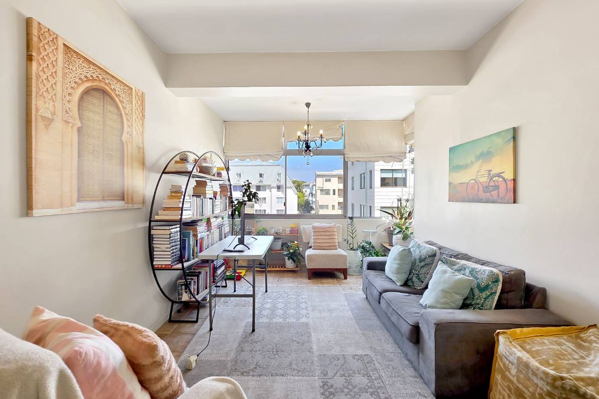A bright and spacious living room featuring large windows that provide natural light and an urban view.