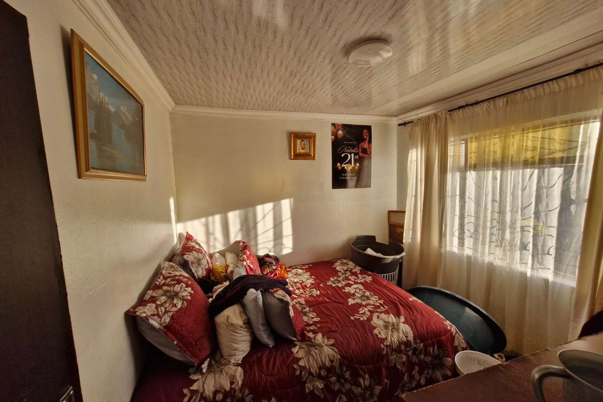 A bedroom featuring a textured ceiling, large window with curtains, and neutral wall finishes.