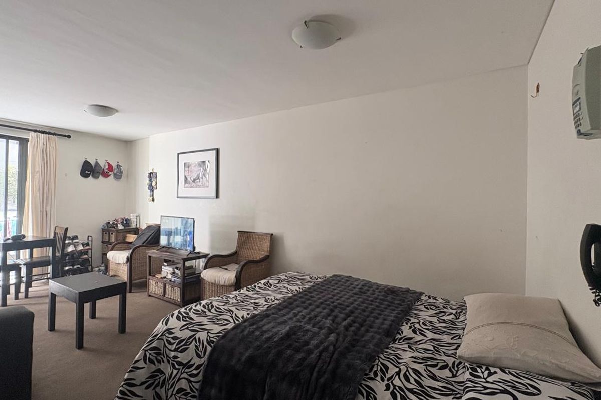 A bedroom featuring neutral walls, carpeted flooring, and a sliding glass door providing access to an outdoor area.