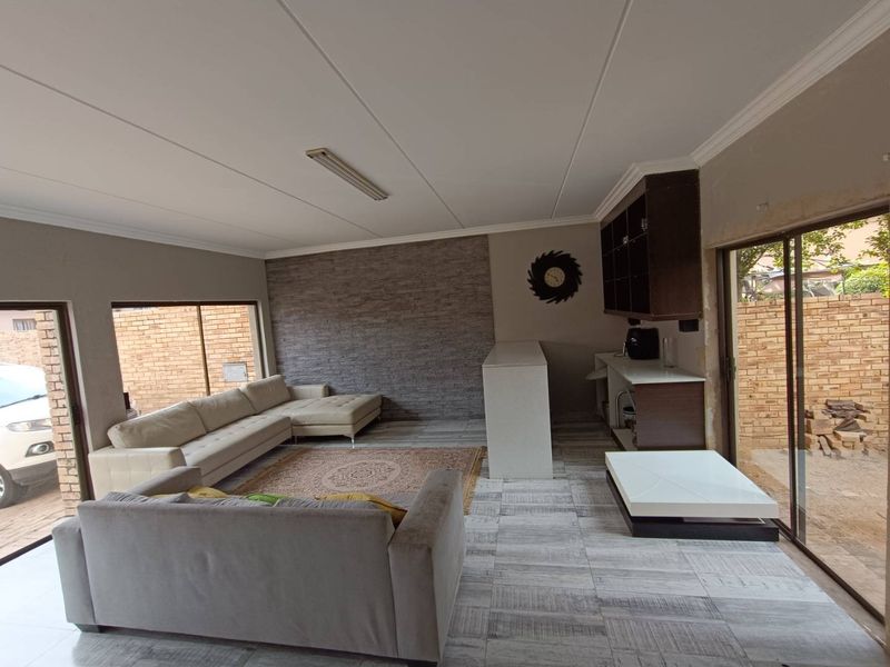 Open plan living area featuring a stone veneer accent wall, built-in bar cabinetry, and large sliding glass doors providing access to the exterior.