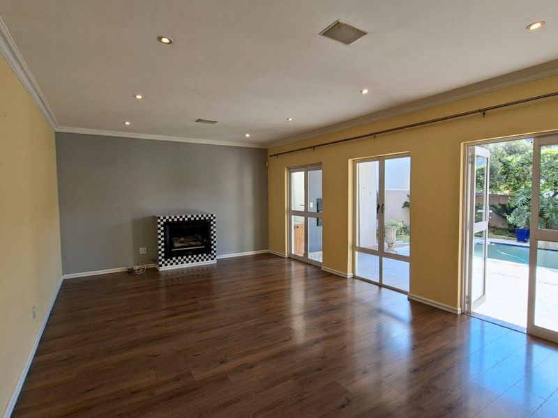 Spacious living room featuring laminate flooring, a built-in fireplace, and large sliding glass doors providing direct access to the pool area.