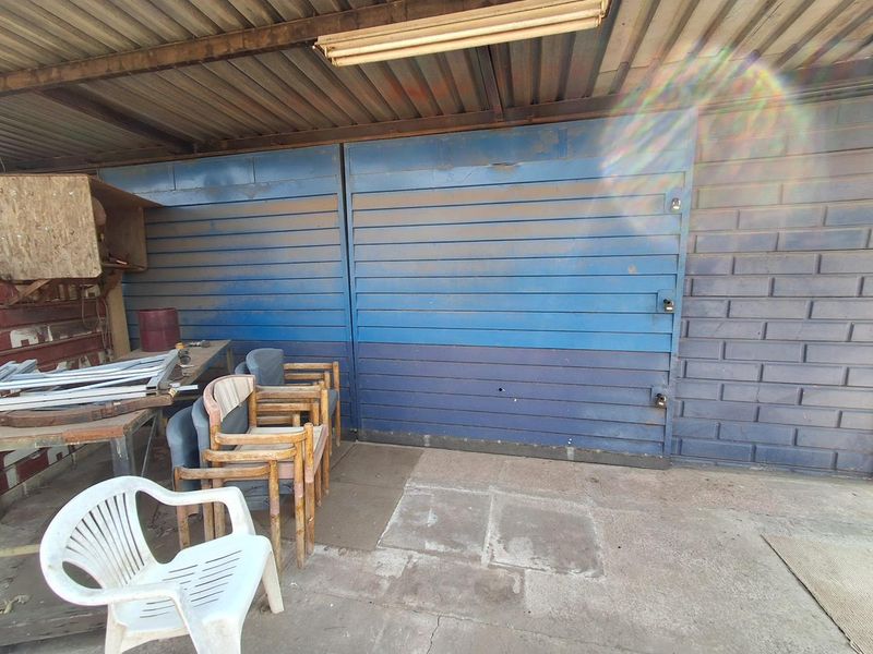 A functional garage space featuring metal doors, concrete flooring, and exposed brickwork, providing secure storage or workshop potential.