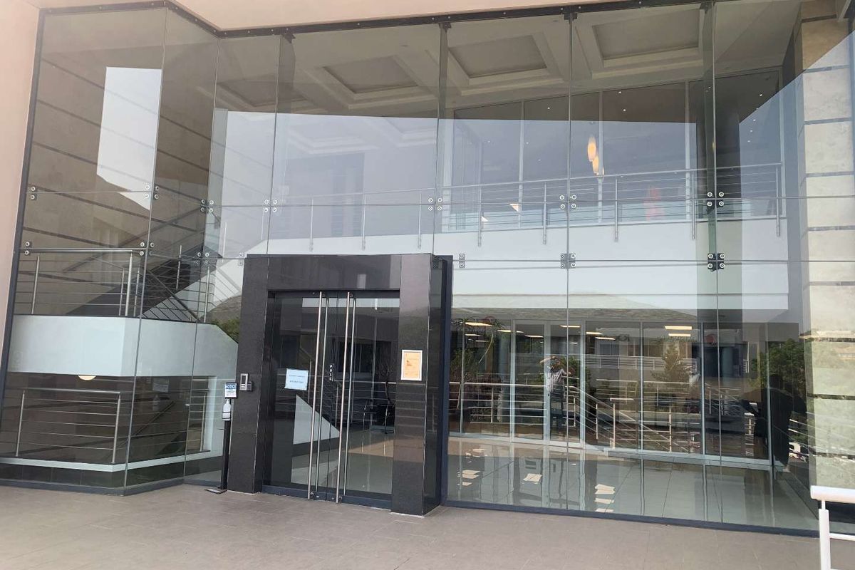 Modern office building entrance featuring a prominent glass facade, polished stone door frame, and a spacious, light-filled lobby area.