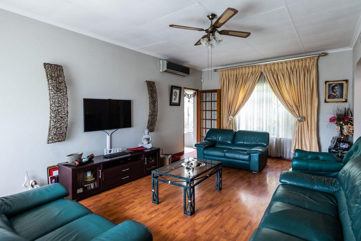 A comfortable living room featuring laminate wood flooring, a ceiling fan, and a wall-mounted air conditioning unit.