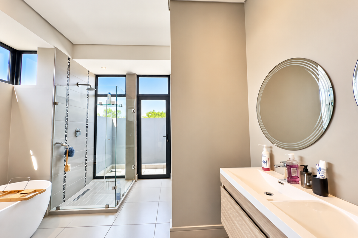 Modern bathroom featuring a freestanding bathtub, walk-in glass shower, and a sleek double vanity with integrated sinks and contemporary finishes.