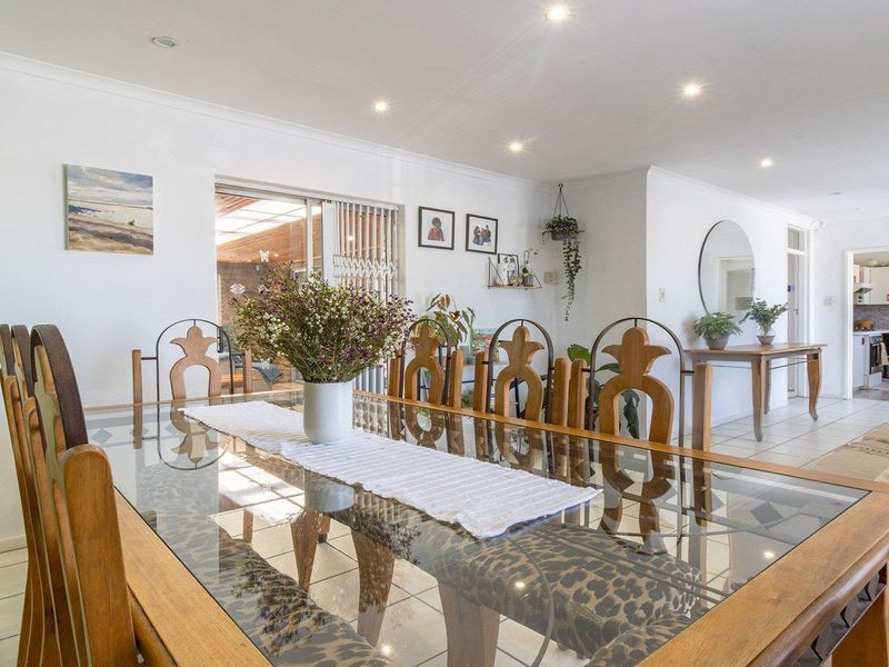 Spacious open-plan living and dining area featuring tiled flooring, recessed downlights, and a sliding glass door leading to an outdoor space.