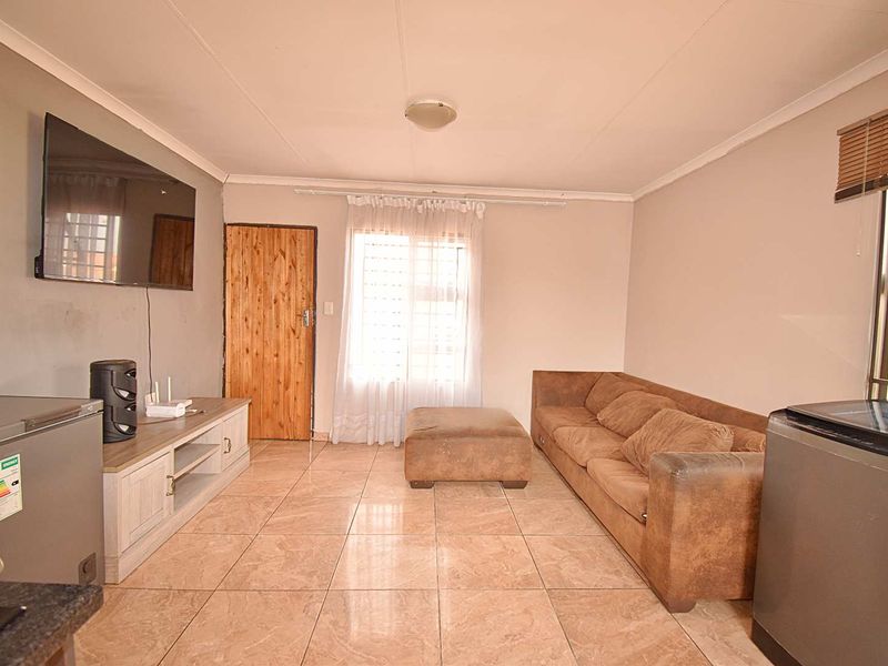 A living room featuring tiled flooring, coved ceilings, and security bars on the windows, providing a functional and secure living space.