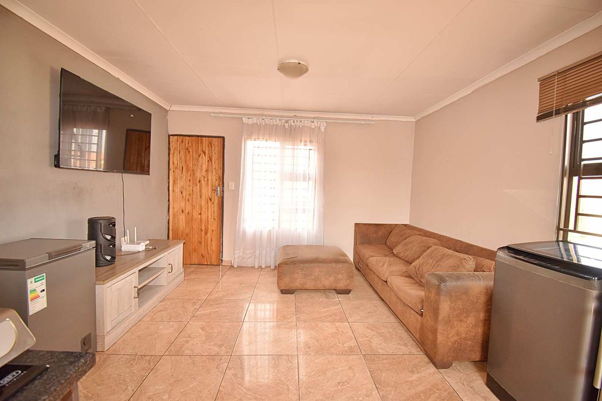 A living room featuring tiled flooring, coved ceilings, and security bars on the windows, providing a functional and secure living space.