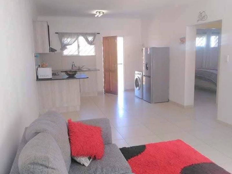 Open-plan living area featuring tiled flooring and a functional kitchen space with built-in cabinetry and an extractor fan.