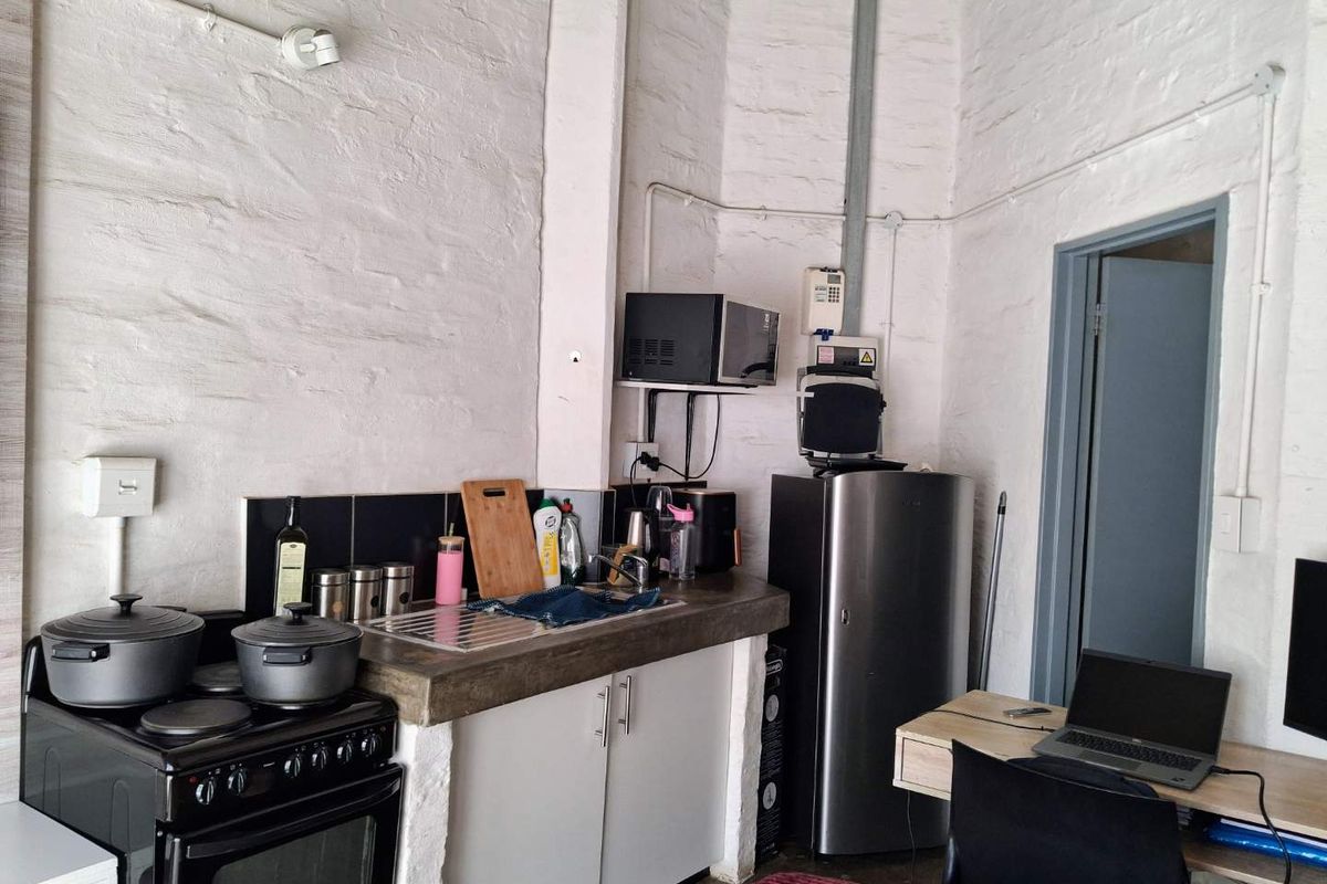 Compact kitchen area featuring a concrete countertop, electric stove, and exposed brick walls, offering a rustic industrial aesthetic.
