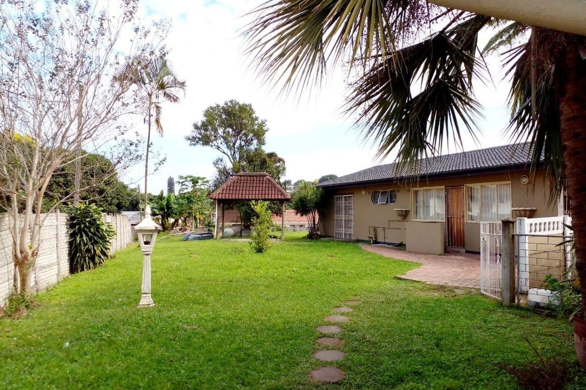 Spacious rear garden featuring a paved patio area, a detached gazebo, and established lawn, providing a private outdoor space for relaxation.