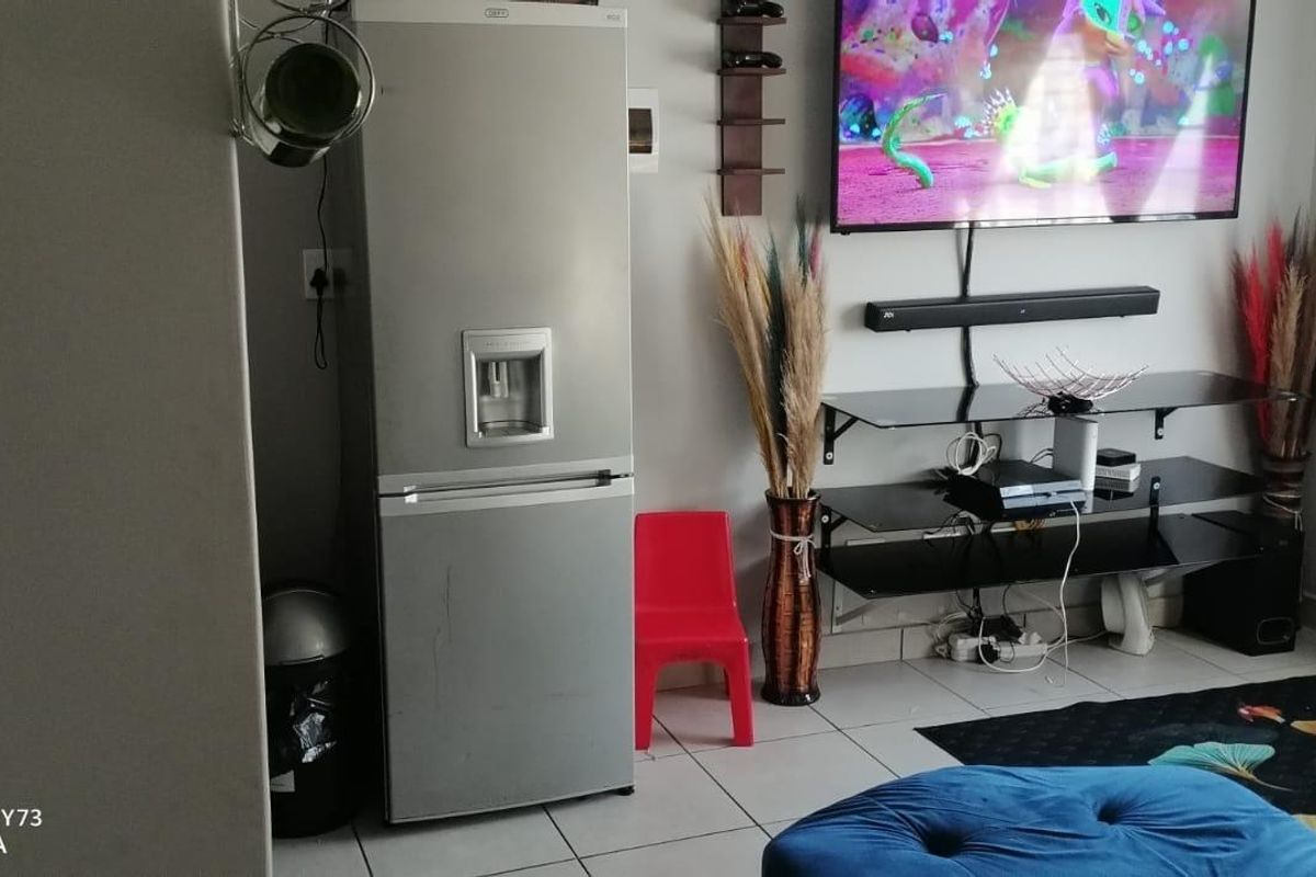 A living room area featuring tiled flooring and a wall-mounted television setup.