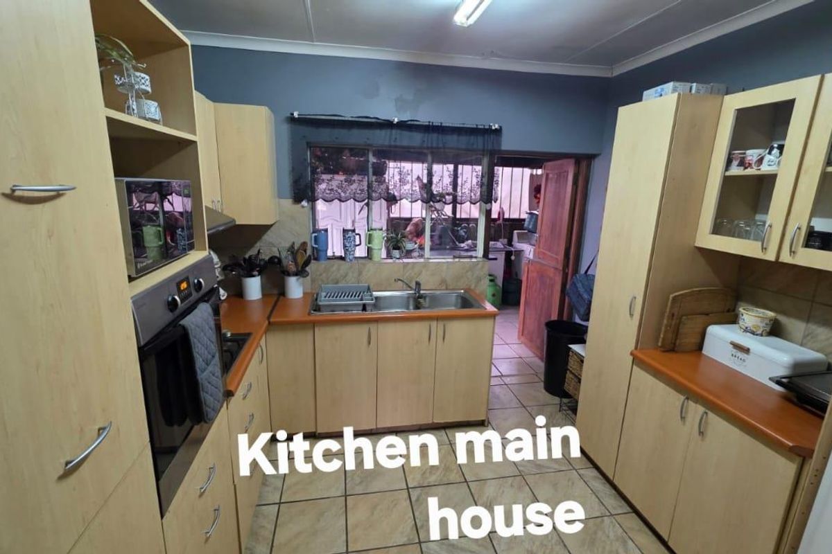 Functional kitchen featuring light wood-tone cabinetry, laminate countertops, a double stainless steel sink, and tiled flooring with a built-in oven.