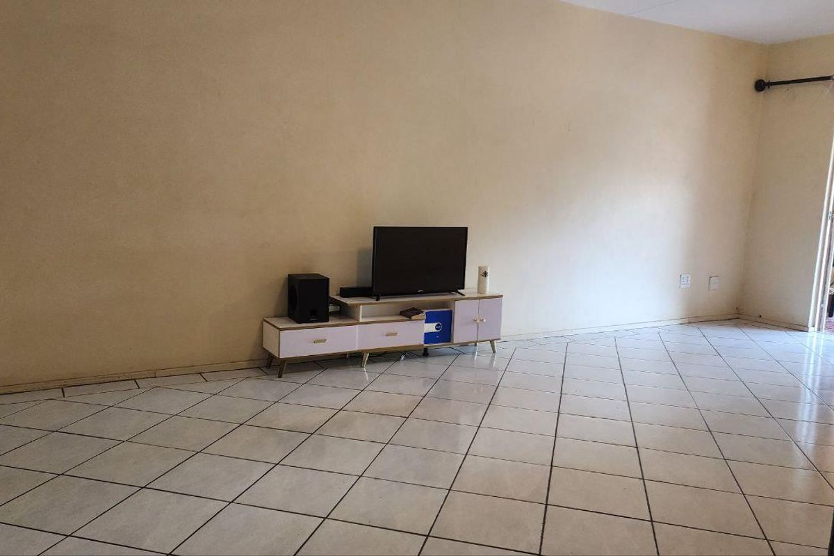 Spacious living area featuring neutral wall tones and tiled flooring, with direct access to an outdoor patio area.