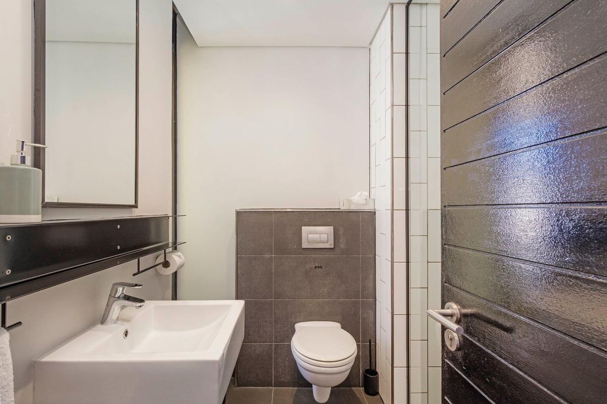 A modern, compact bathroom featuring a wall-mounted toilet, a sleek vanity basin, and contemporary tiled finishes.