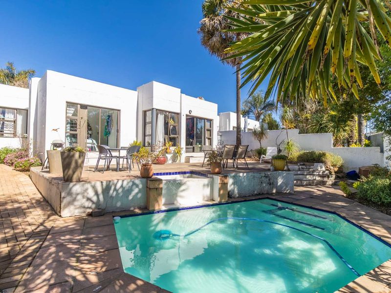 Rear exterior view featuring a raised patio area, swimming pool, and direct access to the home through sliding glass doors.