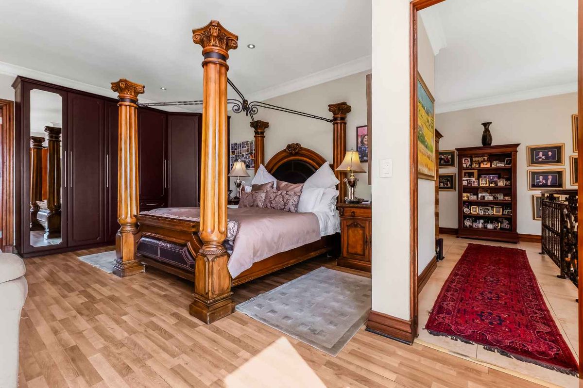 Spacious bedroom featuring laminate flooring, built-in wardrobes, and decorative architectural columns, offering a warm and traditional aesthetic.