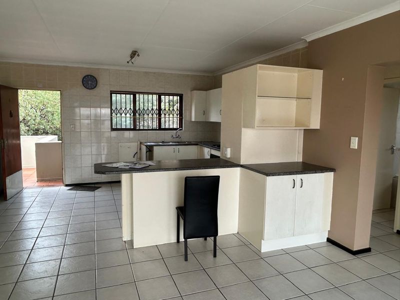 Open plan kitchen area featuring tiled flooring, breakfast bar, and functional cabinetry, providing a practical layout for daily living and meal preparation.