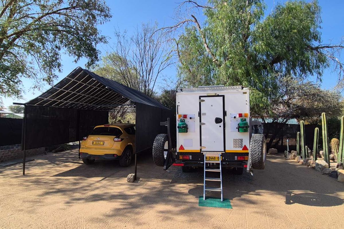 Outdoor area featuring a covered carport structure and gravel driveway, providing convenient off-street parking space.