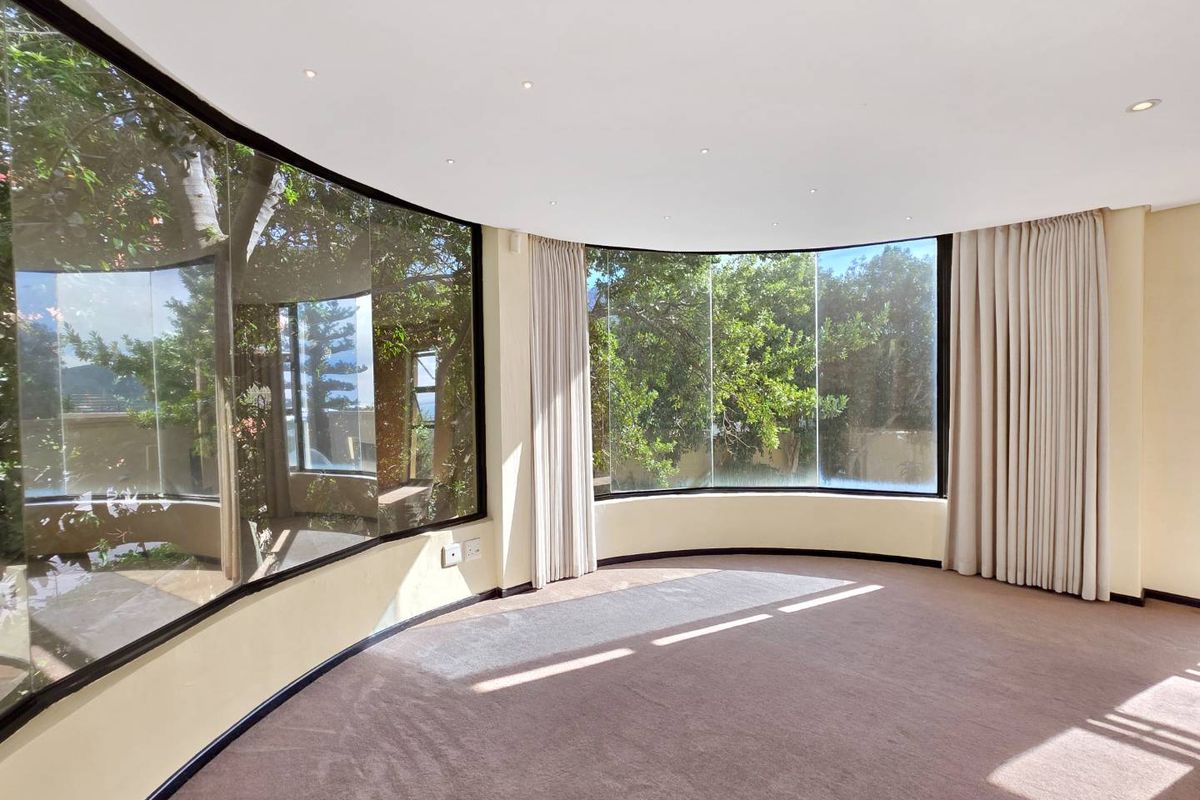 Spacious living area featuring expansive curved floor-to-ceiling windows that provide abundant natural light and pleasant garden views.