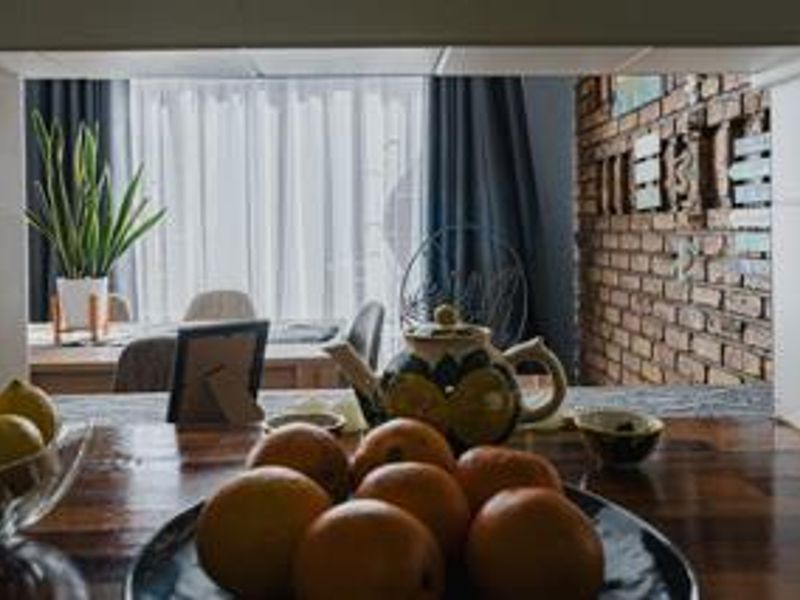 Open plan living area featuring a rustic exposed brick wall and a convenient kitchen pass-through window with a timber countertop.