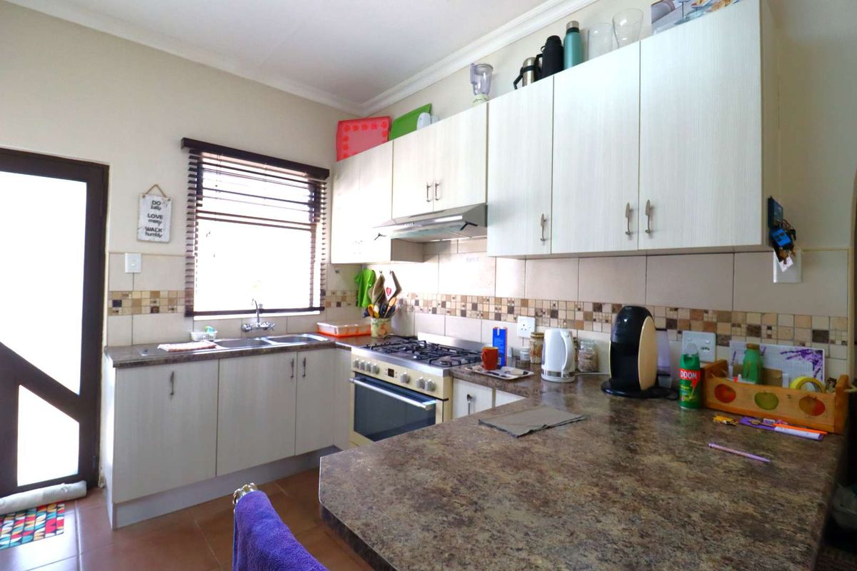 Functional kitchen featuring laminate cabinetry, gas hob with extractor fan, tiled backsplash, and ample countertop space with direct access to the exterior.