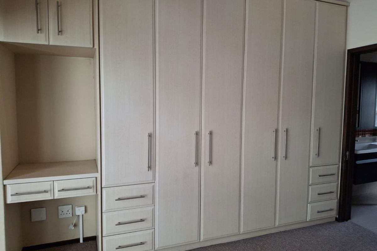A bedroom featuring extensive light-toned built-in cabinetry with integrated storage and a vanity desk area.