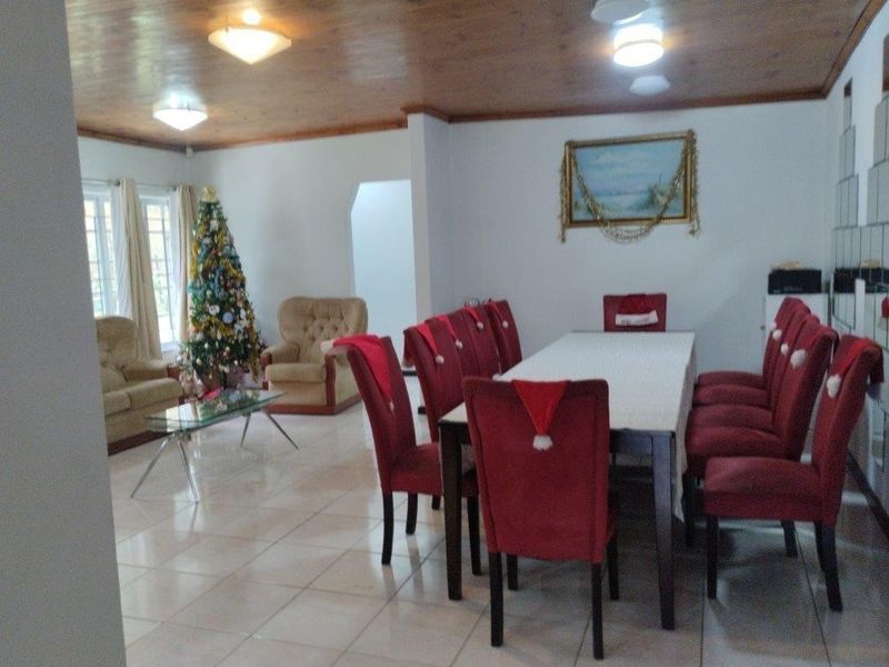 Spacious open-plan living and dining area featuring tiled flooring and a timber-paneled ceiling, offering a versatile layout for family gatherings.