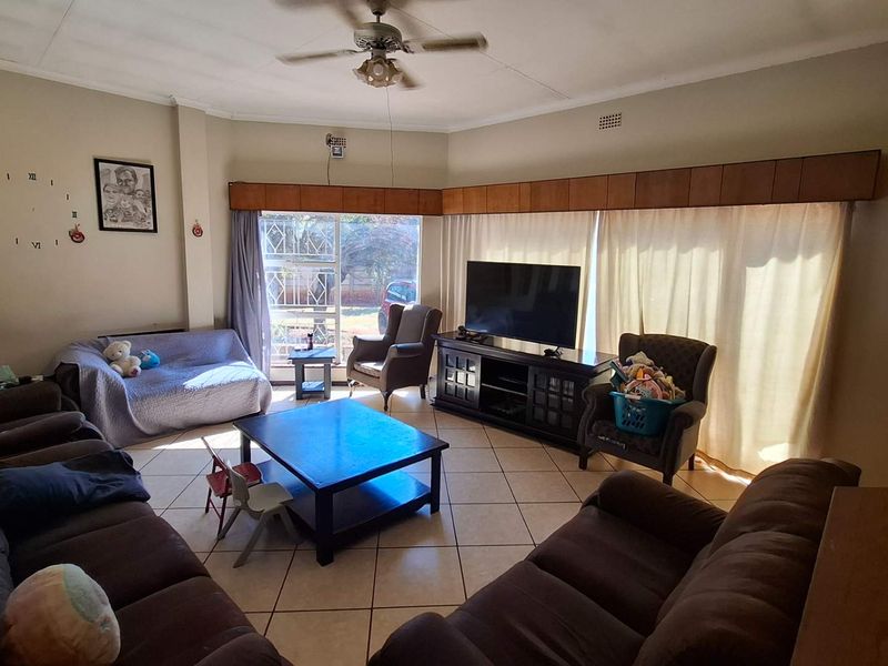 Spacious living room featuring tiled flooring, a ceiling fan, and large sliding glass doors providing natural light and access to the exterior.