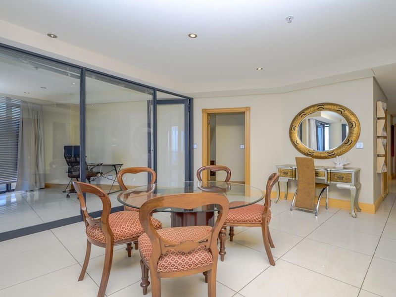 Open plan living area featuring large glass partition walls, neutral tiled flooring, and recessed downlighting, creating a bright and versatile space.