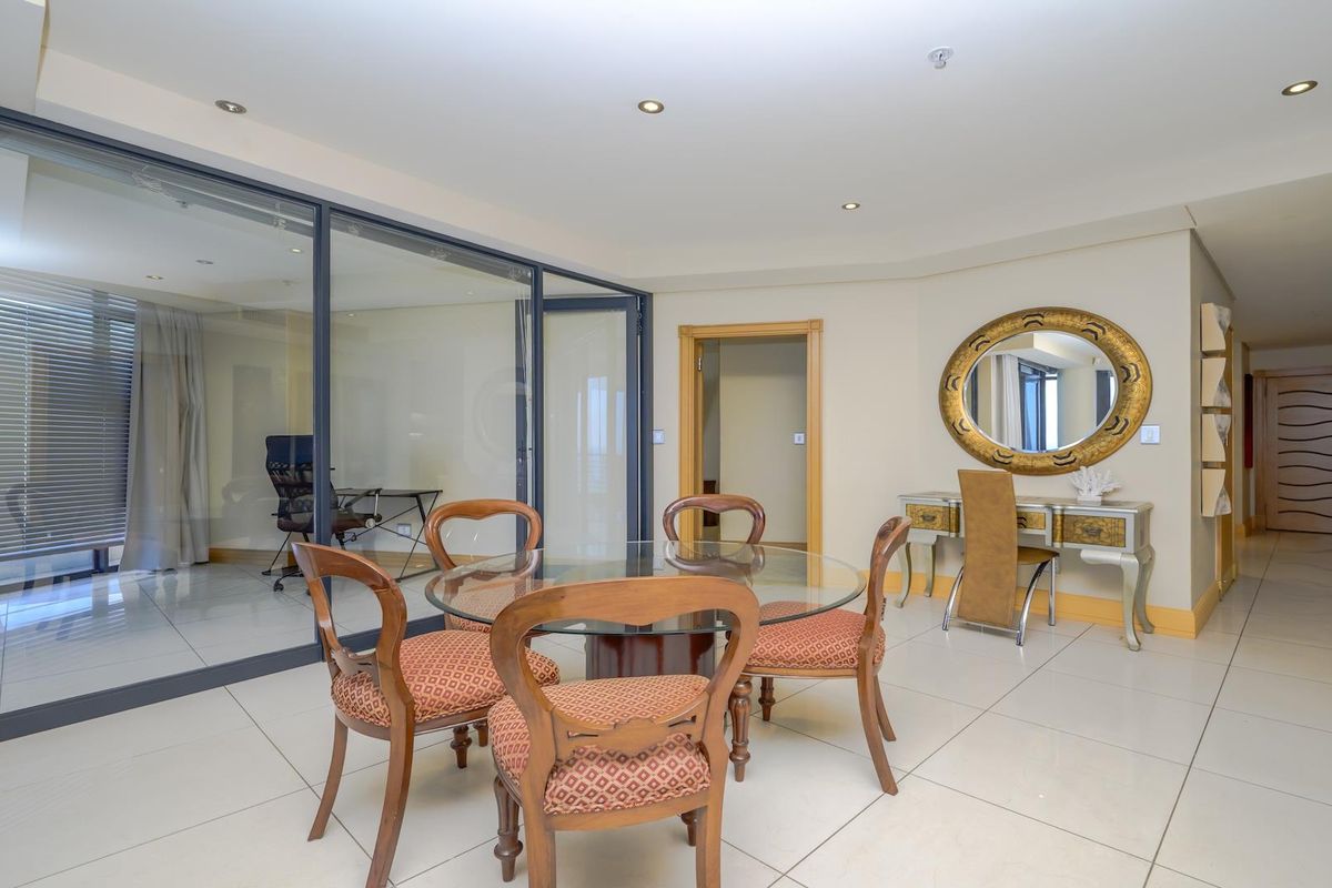 Open plan living area featuring large glass partition walls, neutral tiled flooring, and recessed downlighting, creating a bright and versatile space.