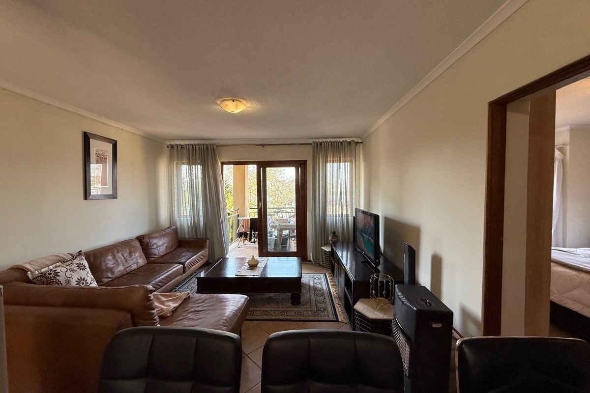 A comfortable living room featuring tiled flooring and a sliding glass door that provides access to an outdoor balcony area.